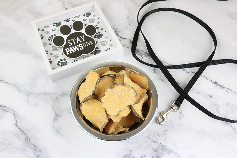 Bowl of sweet potato dog treats with a leash and cute paw picture