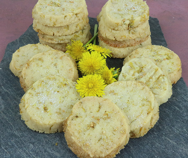 dandelion cookies on a slate tray with flowers