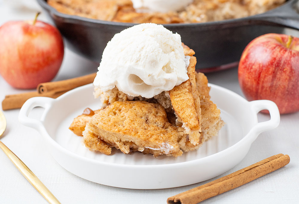 delicious apple pie cobbler recipe in a cast iron pan with the cobbler on a plate