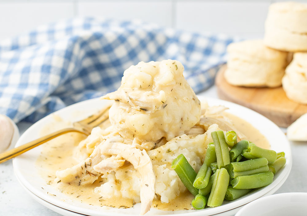 dish of Crockpot Chicken and Gravy on a plate with vegetables